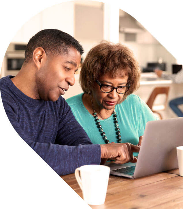 Elderly parent and adult child looking at computer