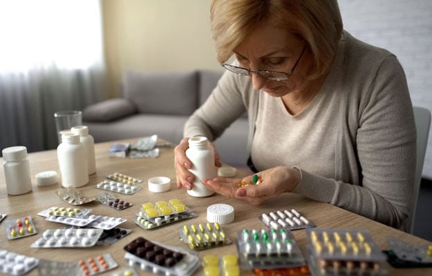 Woman at table looking at a lot of different prescriptions